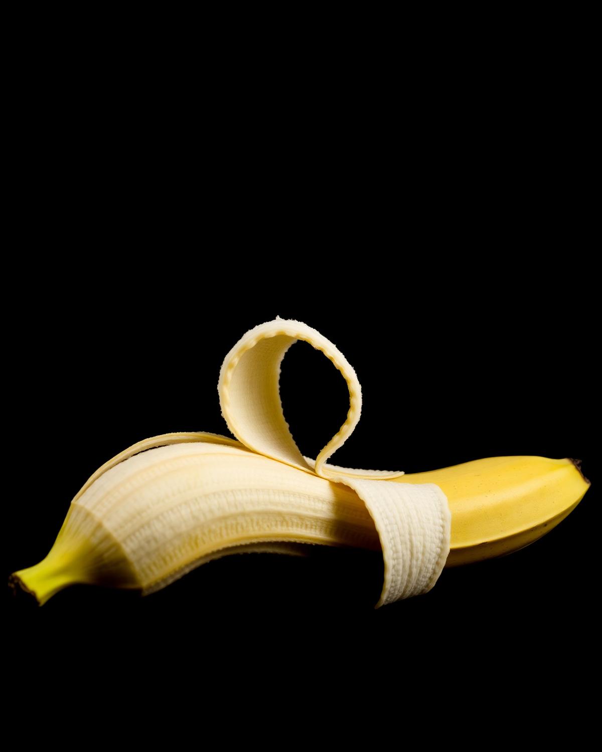 A peeled banana on black background
